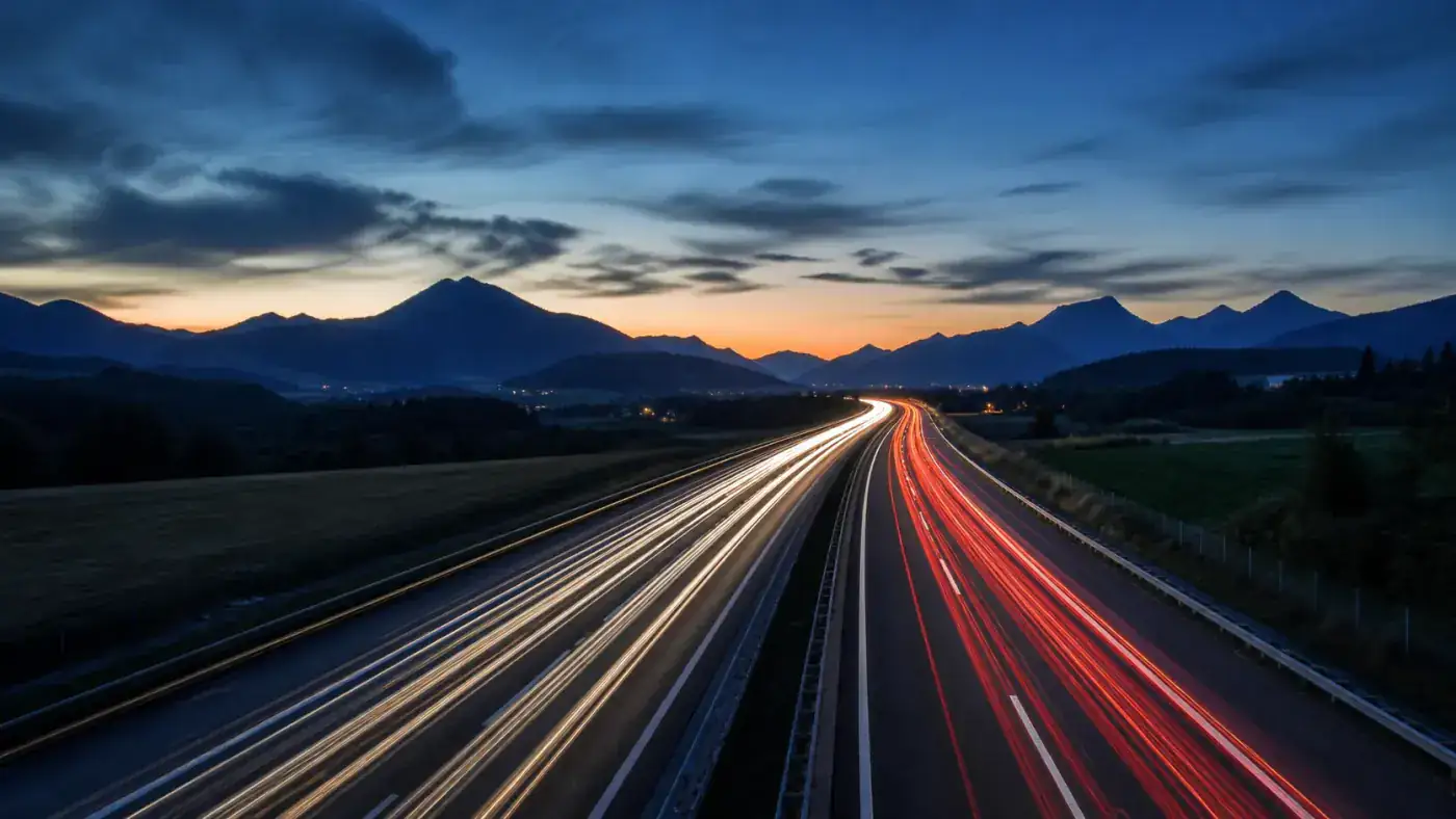 Motorway at dusk with long light trails from headlights and tail lights, the kind of late crossing where a daily vignette can expire mid-drive